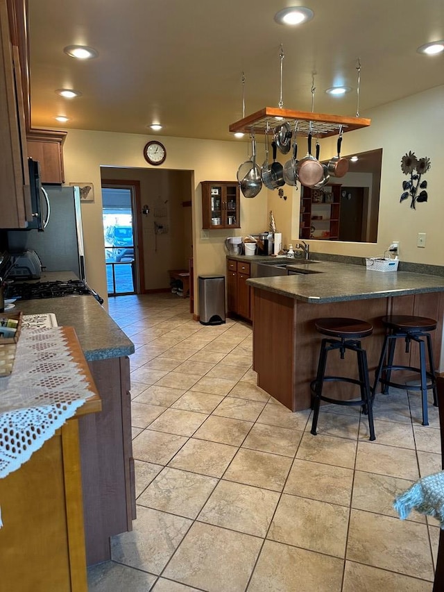 kitchen with a breakfast bar area, kitchen peninsula, sink, and light tile patterned floors