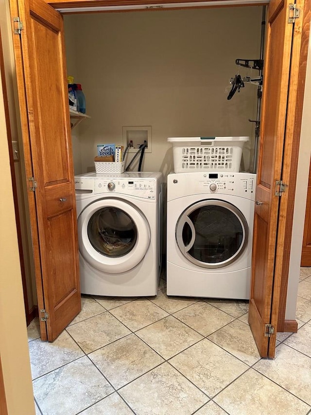 clothes washing area featuring washing machine and dryer and light tile patterned floors