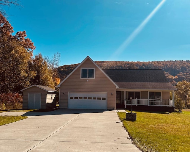 view of front of home with a front lawn, covered porch, a shed, and a garage