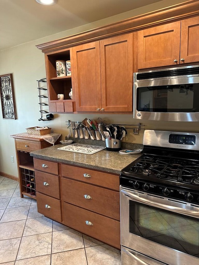 kitchen featuring stainless steel appliances, dark stone countertops, and light tile patterned flooring