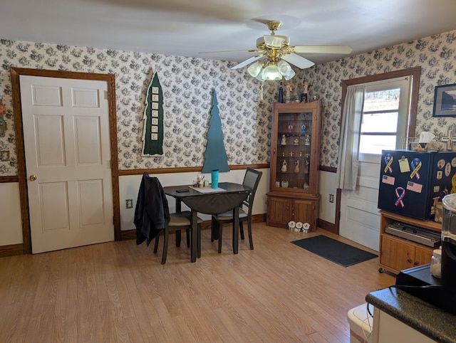 dining area with light wood-type flooring, ceiling fan, baseboards, and wallpapered walls