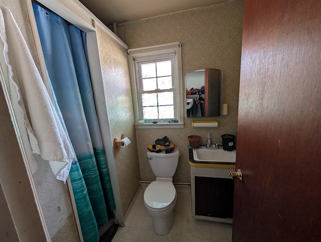 full bathroom featuring toilet, wallpapered walls, tile patterned flooring, and a sink