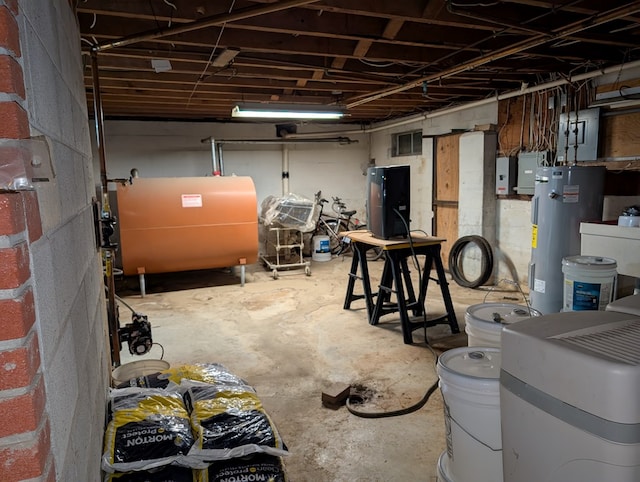 unfinished basement featuring electric panel, electric water heater, visible vents, and heating fuel