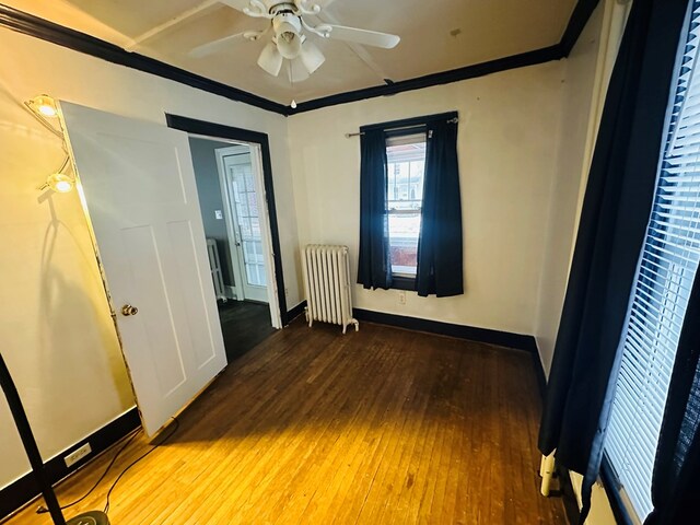 unfurnished bedroom with ceiling fan, radiator, hardwood / wood-style floors, and crown molding