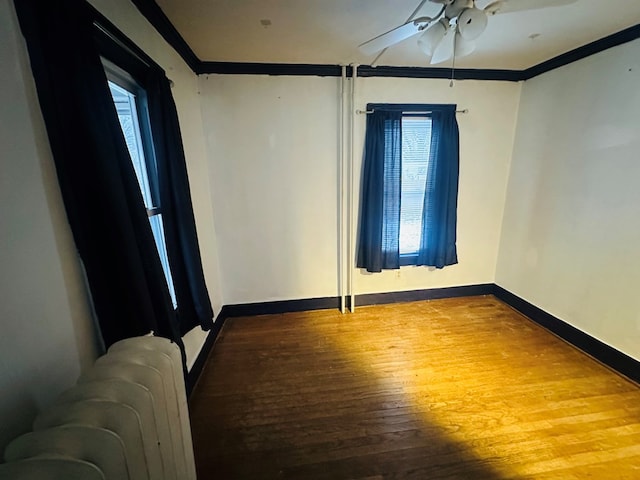 empty room featuring ornamental molding, ceiling fan, radiator, and hardwood / wood-style floors