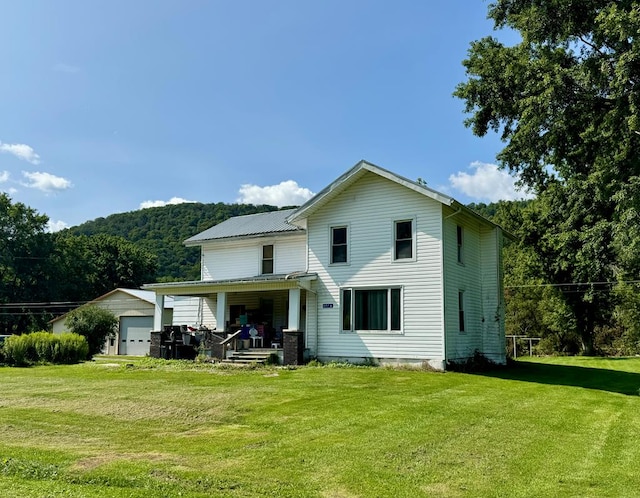 rear view of house featuring a lawn, an outbuilding, a porch, and a garage