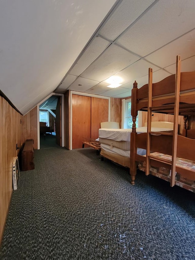 bedroom featuring carpet floors, vaulted ceiling, and wooden walls