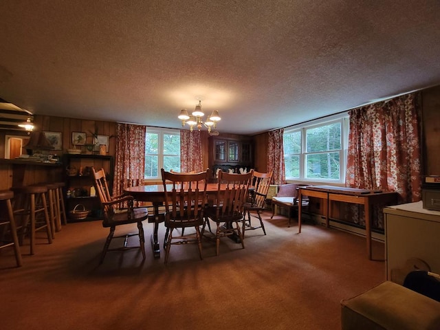 dining space with carpet, a healthy amount of sunlight, a textured ceiling, and a notable chandelier