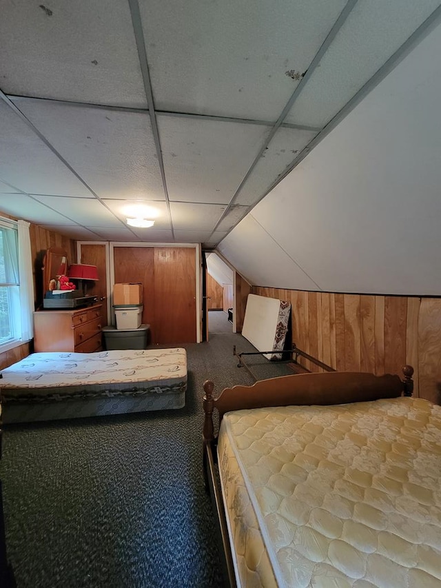 unfurnished bedroom featuring wood walls, carpet floors, and vaulted ceiling