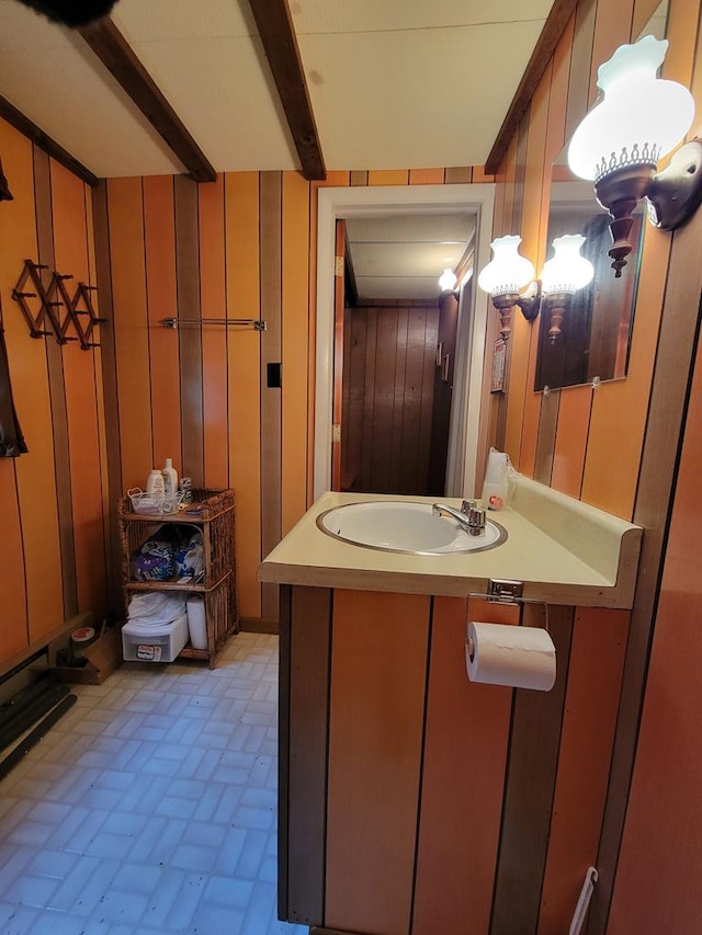 bathroom with beam ceiling, wood walls, and sink