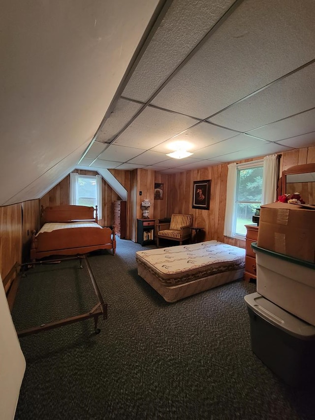 bedroom featuring carpet flooring, a drop ceiling, lofted ceiling, and wood walls