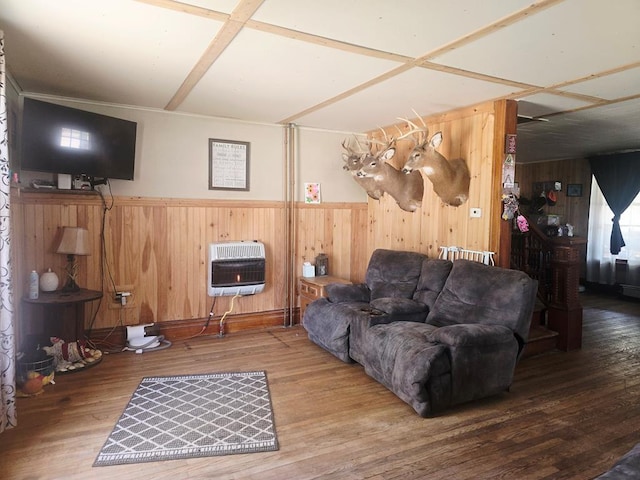 living area with heating unit, wooden walls, and wood finished floors