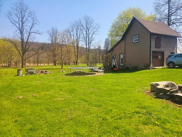 view of yard with a fire pit and a trampoline