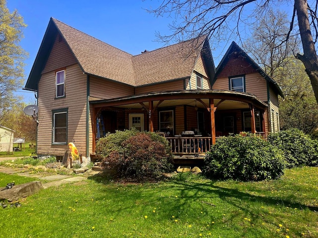 back of house with a yard, a shingled roof, and covered porch