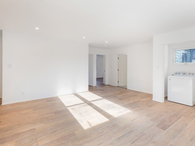 spare room with washer / clothes dryer and light hardwood / wood-style flooring