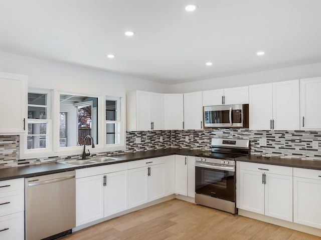 kitchen with stainless steel appliances, white cabinetry, and sink