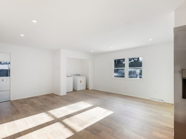 unfurnished living room with independent washer and dryer and light hardwood / wood-style flooring