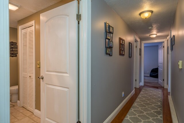 hallway featuring light tile patterned floors and a textured ceiling