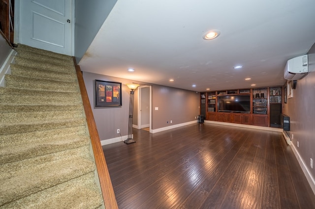 unfurnished living room featuring a wall mounted air conditioner, built in shelves, and dark hardwood / wood-style flooring