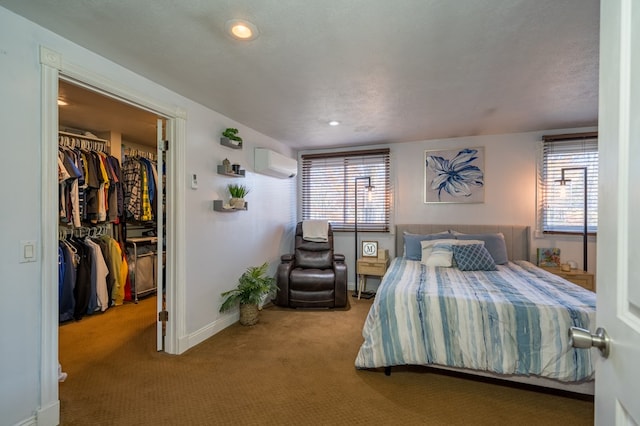 carpeted bedroom with an AC wall unit, a spacious closet, a closet, and a textured ceiling