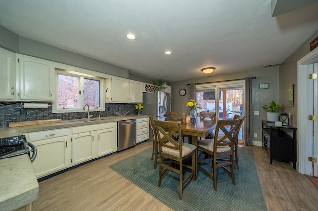 kitchen with white cabinets, light wood-type flooring, sink, and appliances with stainless steel finishes