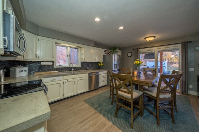 kitchen with backsplash, stainless steel appliances, light hardwood / wood-style flooring, and sink