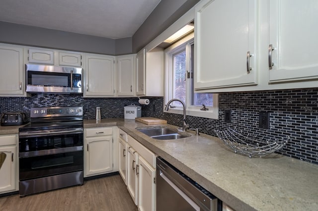 kitchen with decorative backsplash, sink, white cabinets, and appliances with stainless steel finishes