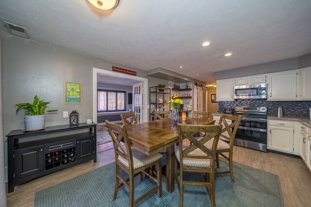 dining space with hardwood / wood-style floors and a textured ceiling