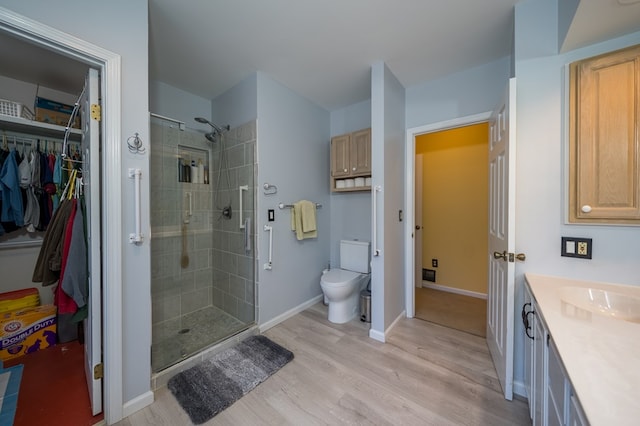 bathroom with vanity, hardwood / wood-style floors, a shower with door, and toilet