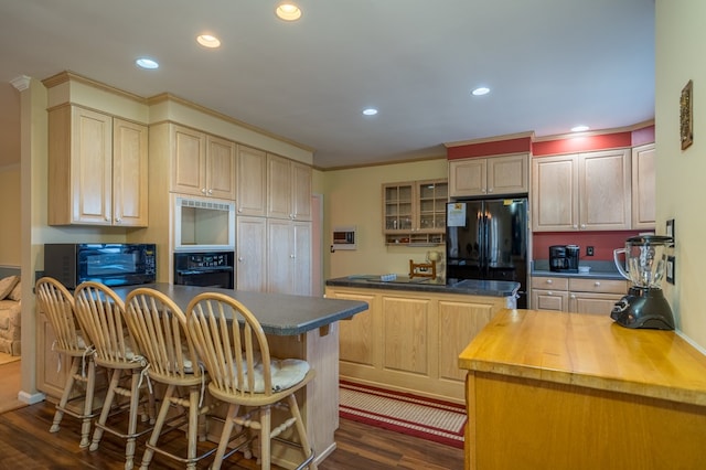 kitchen with a kitchen island, a breakfast bar, wooden counters, black appliances, and dark wood-type flooring