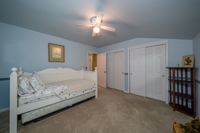 carpeted bedroom featuring multiple closets, lofted ceiling, and ceiling fan