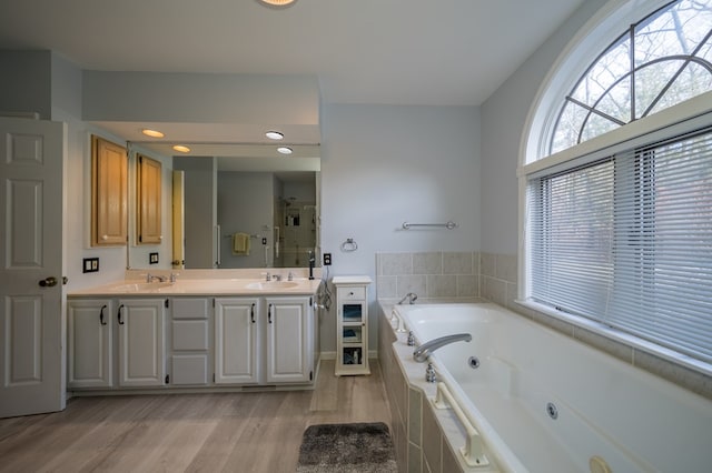 bathroom with hardwood / wood-style flooring, vanity, and shower with separate bathtub