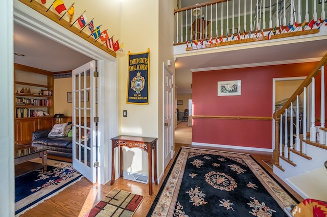 entrance foyer featuring crown molding, hardwood / wood-style flooring, and a high ceiling