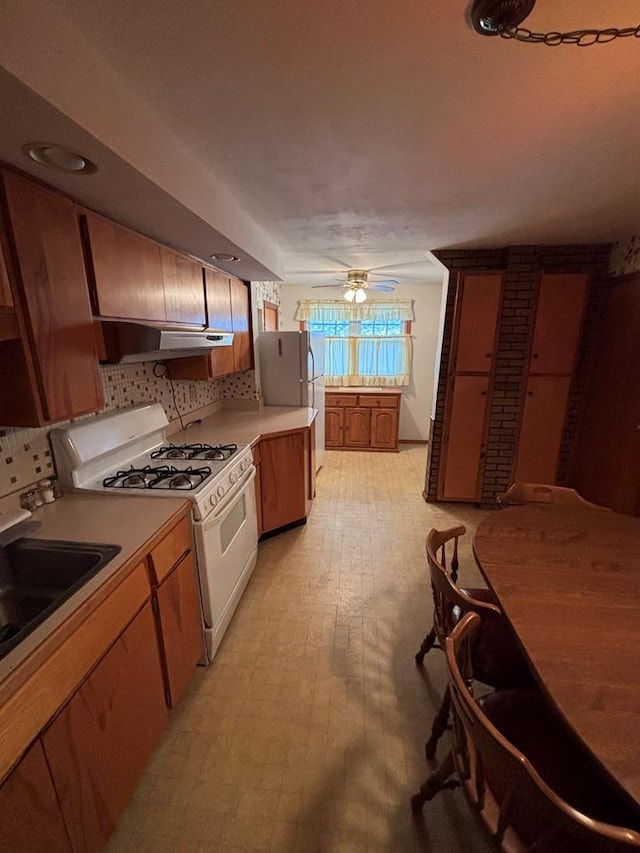 205 E Main St, Elkland, PA 16920 - kitchen with tasteful backsplash, a sink, white appliances, light countertops, and under cabinet range hood
