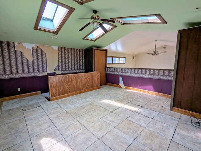 additional living space featuring vaulted ceiling with skylight, ceiling fan, and baseboards