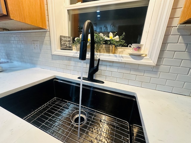 interior details featuring light countertops, brown cabinetry, a sink, and decorative backsplash