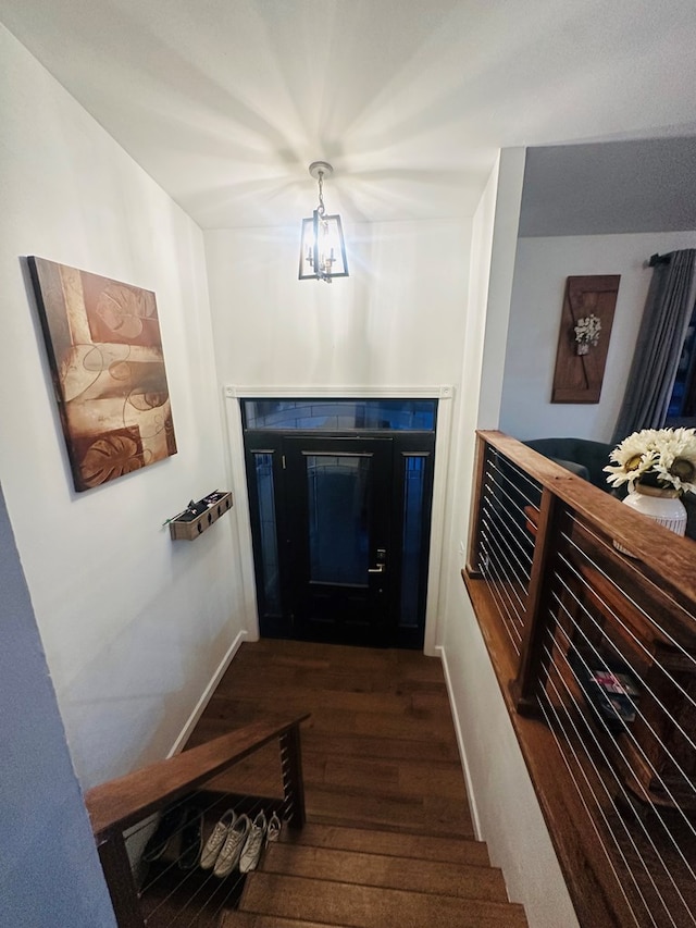 interior space with a chandelier, dark wood-style flooring, baseboards, and stairs