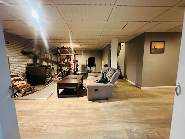 interior space with light wood-style flooring, a wood stove, and baseboards