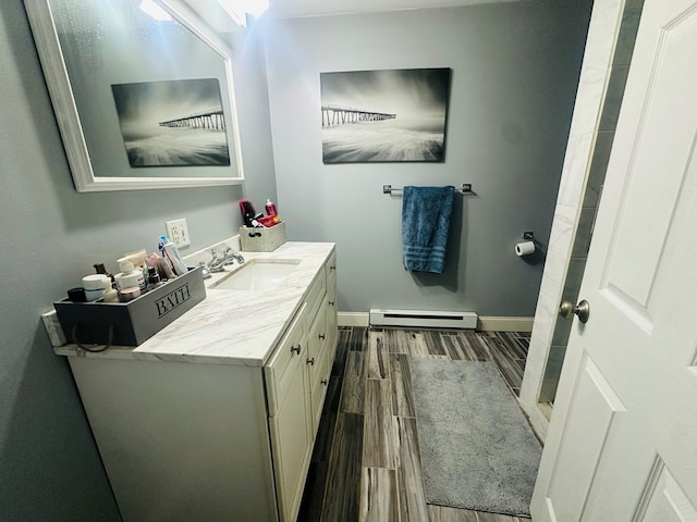 bathroom with wood-type flooring, baseboard heating, and vanity