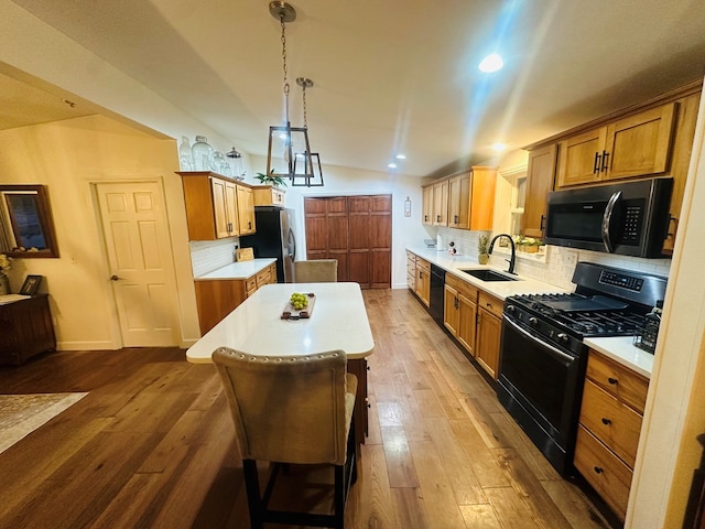 kitchen with black appliances, light countertops, a sink, and a center island