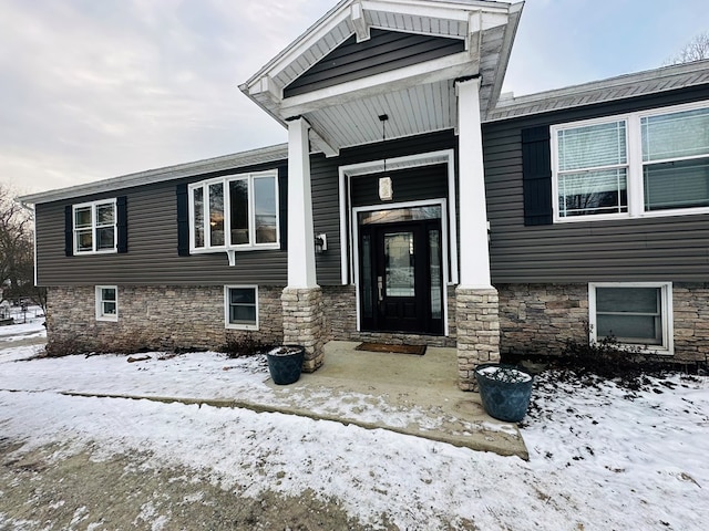 snow covered property entrance with stone siding