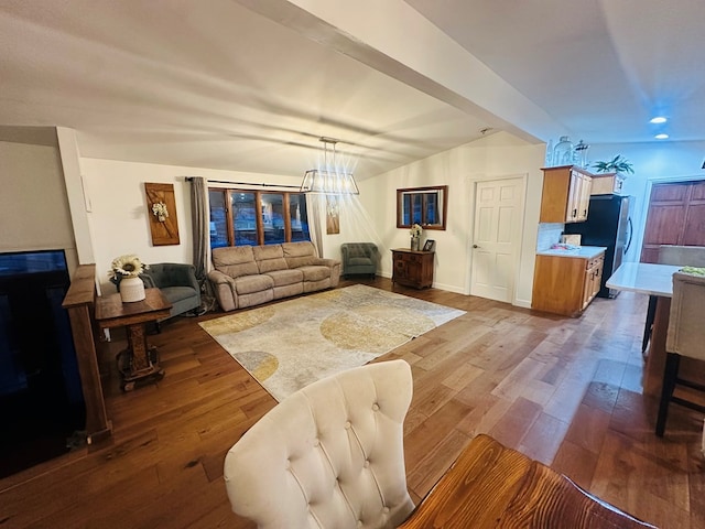 living room featuring a chandelier, beamed ceiling, wood finished floors, and baseboards