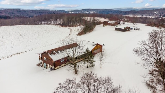 snowy aerial view with a mountain view and a view of trees