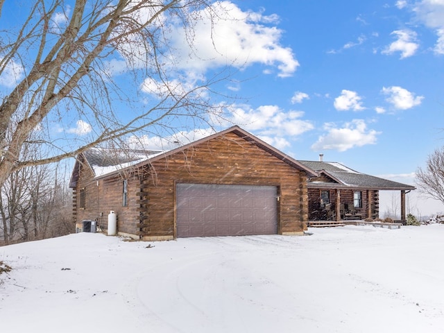 view of front of house with log exterior, an attached garage, and central AC unit