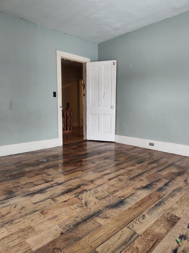 spare room with healthy amount of natural light and dark wood-type flooring