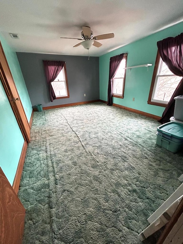 carpeted spare room featuring a wealth of natural light and ceiling fan