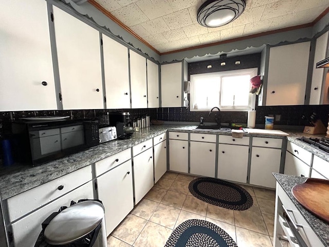 kitchen with tasteful backsplash, white cabinetry, and sink