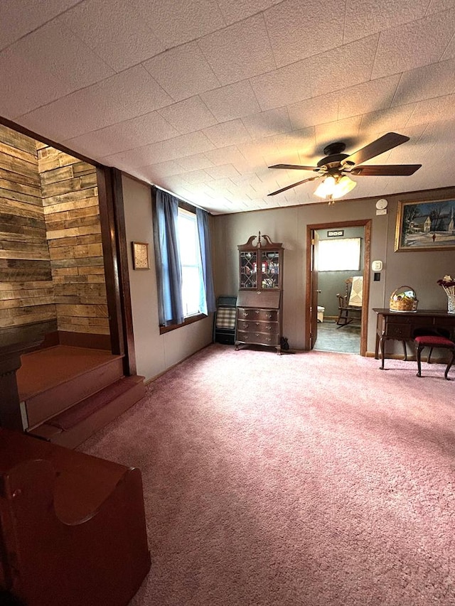 sitting room featuring ceiling fan, carpet, and wooden walls