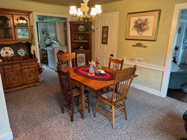 carpeted dining room with a notable chandelier