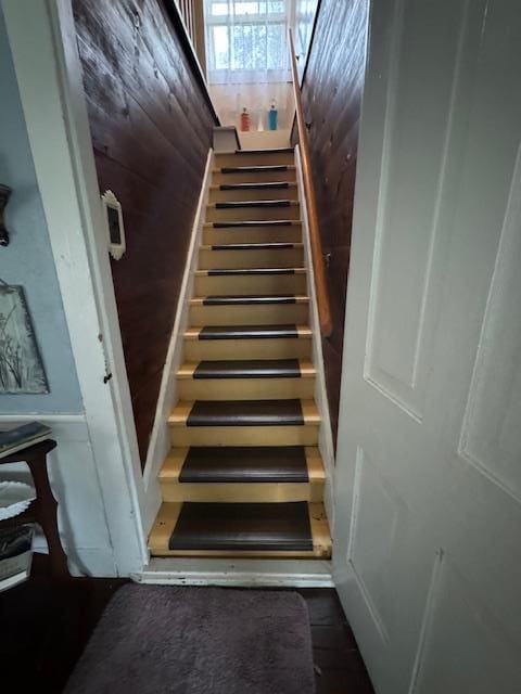 staircase featuring wooden walls